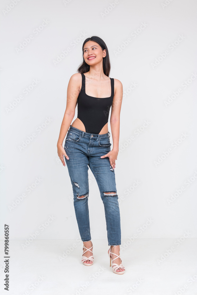 Front view of a sexy young asian woman in a black bodysuit and ripped jeans. Isolated on a white background. Hands on legs, Whole body photo. Front view of a sexy young asian woman in a black bodysuit and ripped jeans. Isolated on a white background. Hands on legs, Whole body photo.