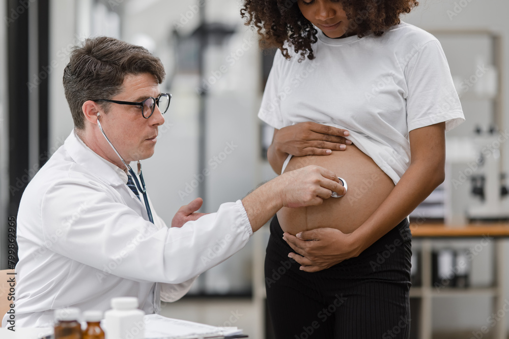 Male doctor examining a pregnant African American woman at the hospital. Male doctor examining a pregnant African American woman at the hospital.