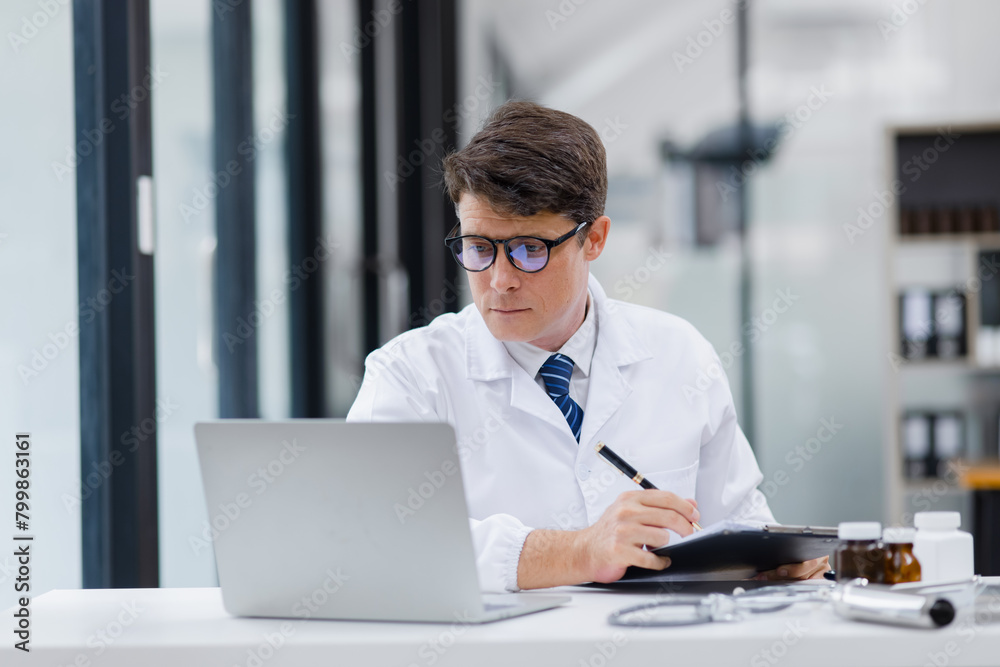 Doctor man working on laptop in the office of the clinic.