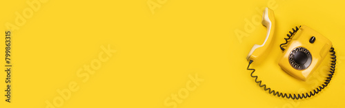 Yellow old stylish Phone, telephone with dial on yellow background copy space for your text horizontal banner top view off-hook phone and your text photo