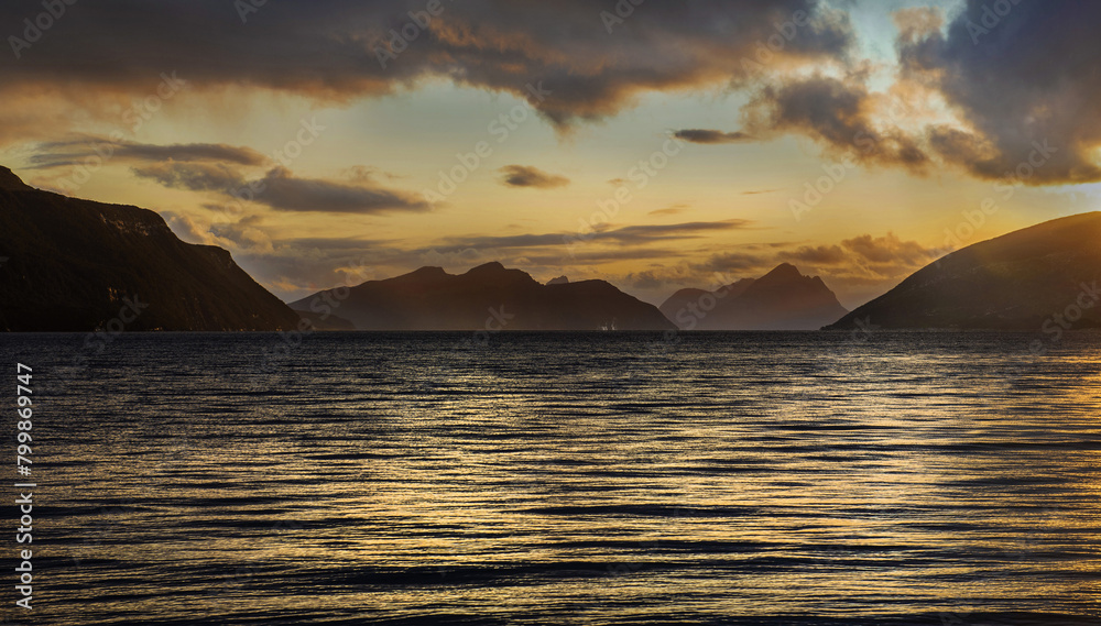 landscape in a Norway fjord at sunset over the sea with hills in back
