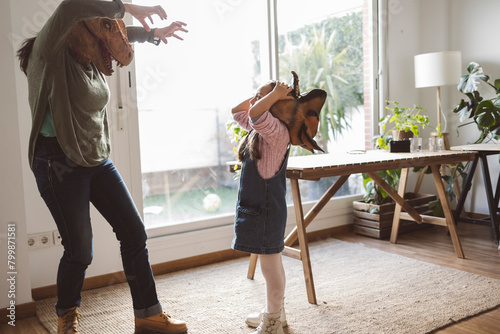 Grandmother and granddaughter wearing animal masks playing together at home photo