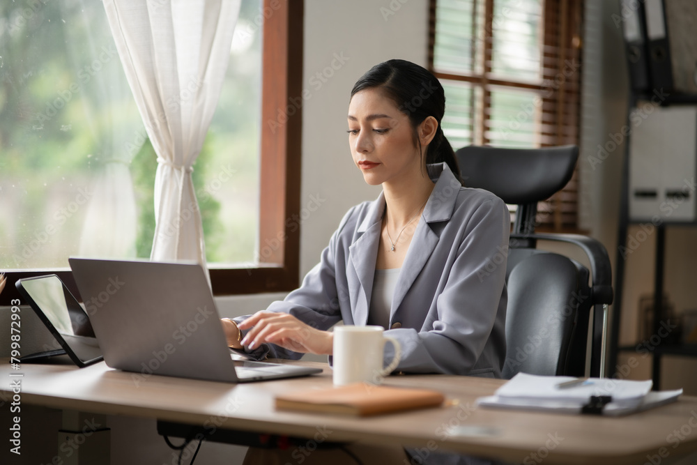 Asian business woman working on computer looking at documents at office Asian business woman working on computer looking at documents at office