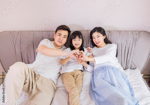 A family of three in the bed in the bedroom © 大 李