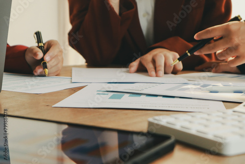 In an office, a woman and a man work together at a desk, using teamwork and communication to succeed in their business meeting.