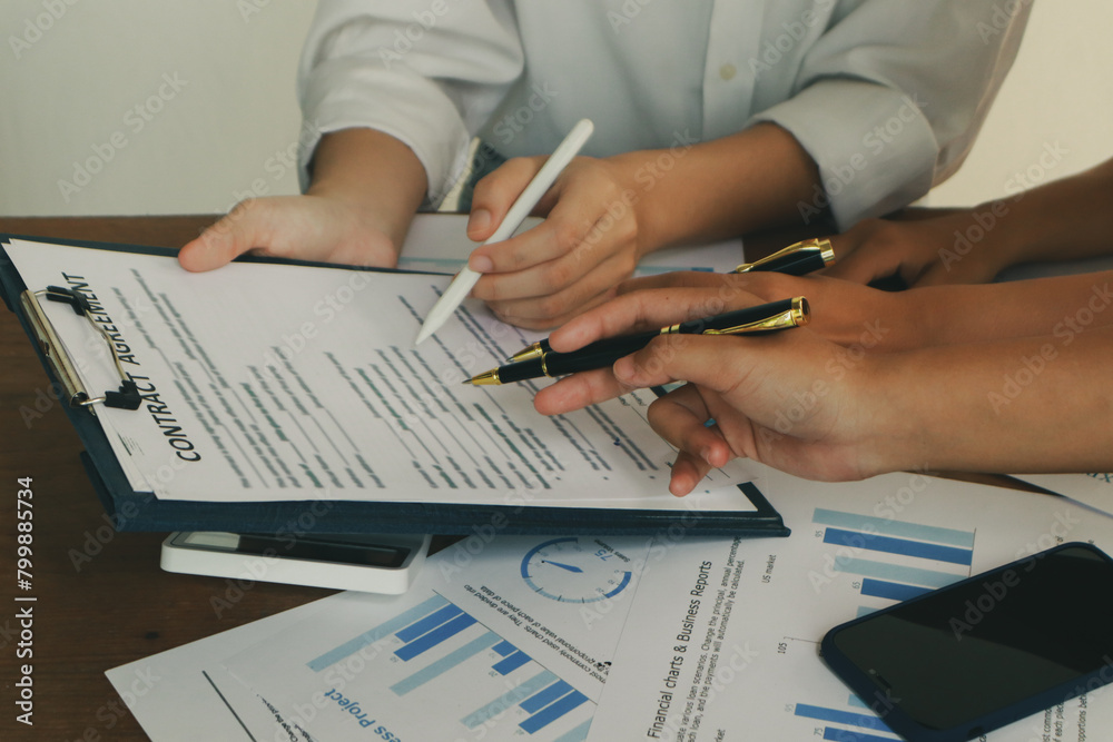 Fototapeta premium In an office, a woman and a man work together at a desk, using teamwork and communication to succeed in their business meeting.