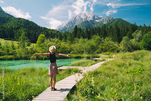 People in nature. Tourist woman with raised arms up in green nature background. View on Zelenci (into English means - green) natural reserve in Slovenia, Europe. Travel, Freedom, Lifestyle concept. photo