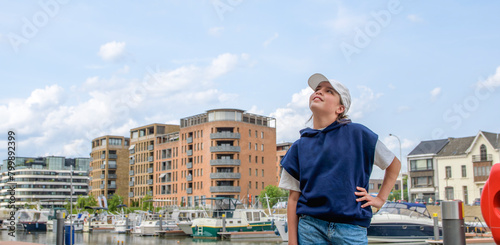 A young girl stands on a pier looking out at the sky. Banner size