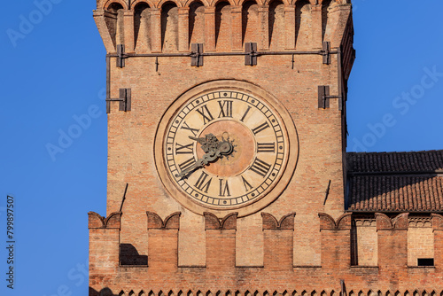 Clear blue skies backdrop the historic clock of Palazzo d'Accursio in Bologna, a testament to Italian craftsmanship and enduring architecture