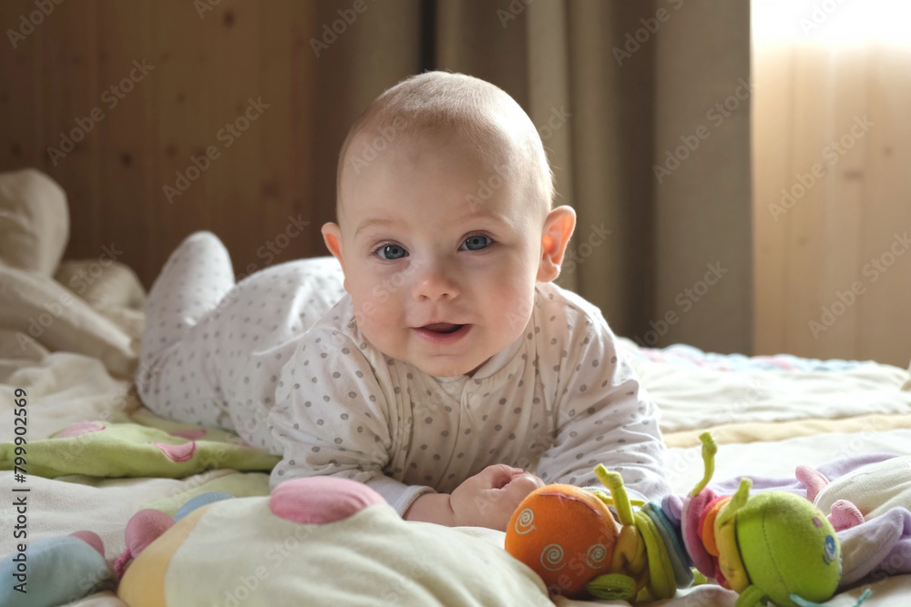Smiling baby girl learning to crawl and playing with colorful toys in white sunny bedroom. Smiling baby girl learning to crawl and playing with colorful toys in white sunny bedroom.