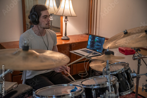 Closeup of drummer in home studio with drum kit and headphones selective focus copy space, cymbals drum kit and laptop