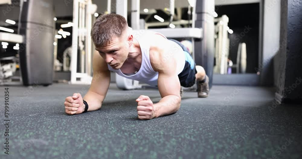 Fit male person does plank pose to strengthen body in modern gym. Fit athlete enjoys intensive workout in modern gym after work slow motion Fit male person does plank pose to strengthen body in modern gym. Fit athlete enjoys intensive workout in modern gym after work slow motion