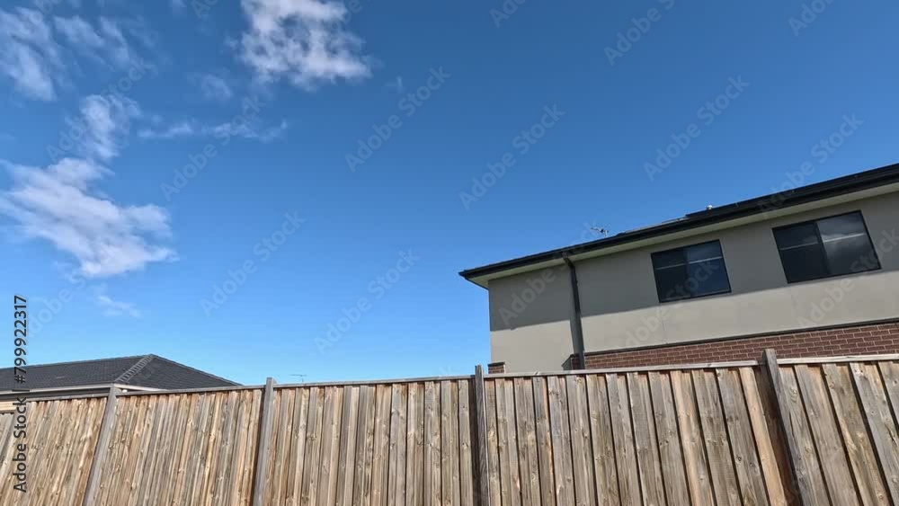 Modern residential suburban houses stand behind wooden garden fences in an Australian neighborhood. Concept of neighbors, housing market, real estate investment, the privacy of private property. Modern residential suburban houses stand behind wooden garden fences in an Australian neighborhood. Concept of neighbors, housing market, real estate investment, the privacy of private property.
