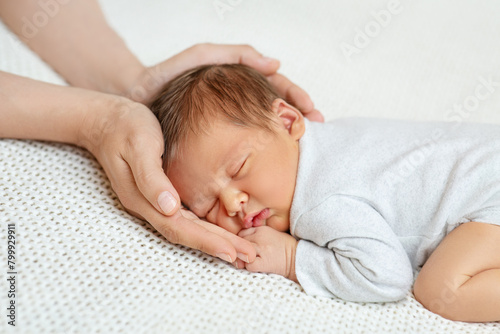 Baby Head in Mother Hands. Mum Love. Sleeping Newborn in Parent Palms over White Blanket. Infant Health Care. Little Child Development