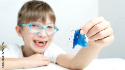 Happy child with a plate for correcting teeth bite