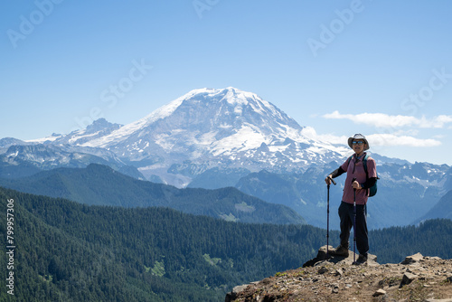 Hiker smiling and looking at the camera with Mount Rainier in the background. Summit Lake trail. Mt Rainier National Park. Washington State.