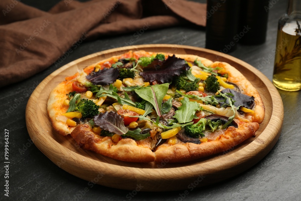 Delicious vegetarian pizza with mushrooms, vegetables and greens on black table