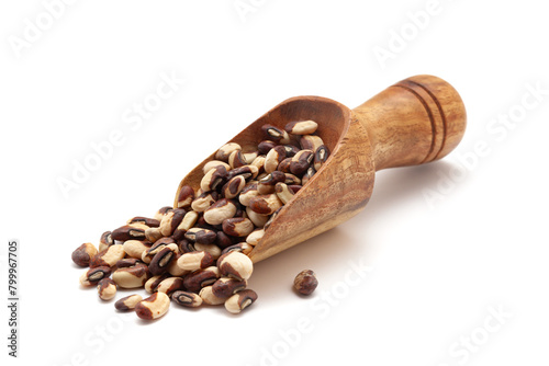 Front view of a wooden scoop filled with dry Organic Beans or Black Eyed Peas (Vigna unguiculata) seeds. Isolated on a white background.