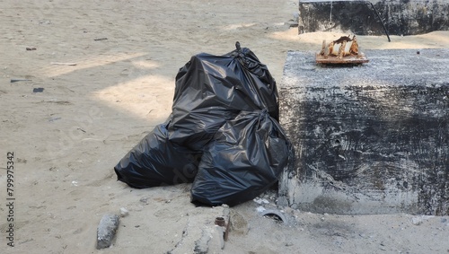 Bunch of tied black plastic garbage disposable bags filled with household junk and waste for recycling and disposal dumped near road or street area for pickup creating environmental pollution. © ECO LENS