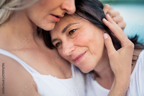 Adult daughter spending time with her mother outdoors. Beautiful daughter holding mother's face lovingly. Unconditional, deep maternal love, Mother's Day.