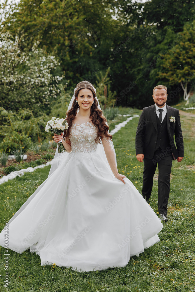 A bride and groom are walking down a grassy path