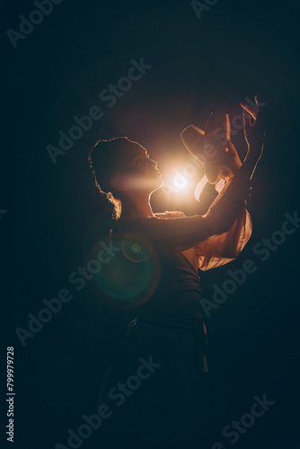 Closeup view to young ballerina holding pointe shoes in her hands on dark background against light.