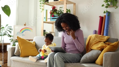 African American mother working remotely taking phone call while taking care of her daughter