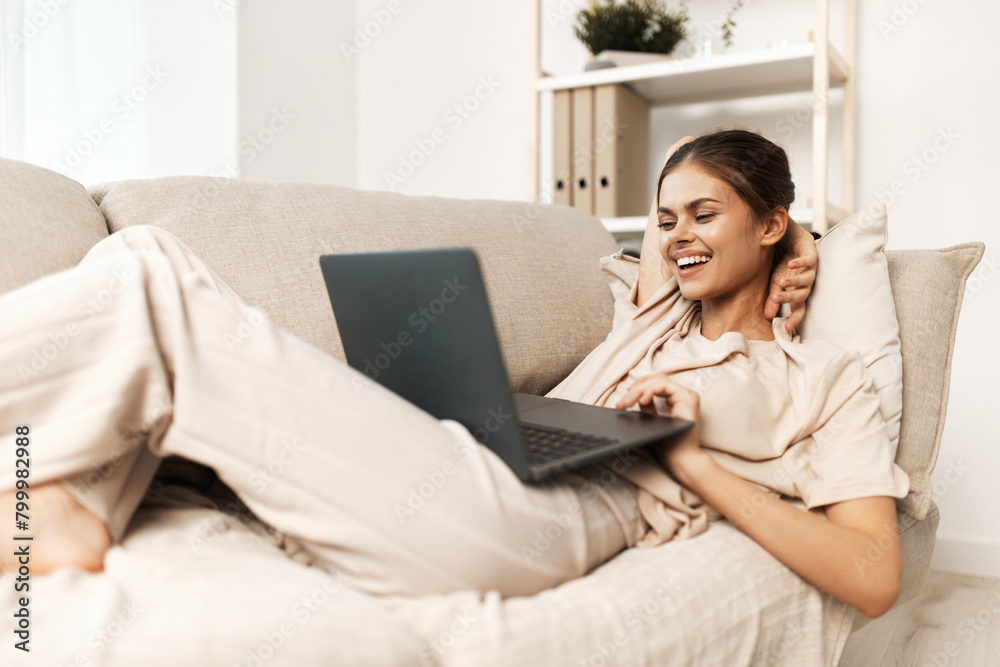 Smiling Woman Working on Laptop at Home: Modern Lifestyle in Cozy Living Room. Smiling Woman Working on Laptop at Home: Modern Lifestyle in Cozy Living Room.