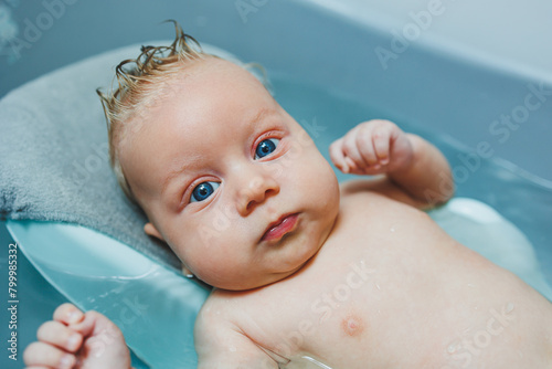 The baby lies in the bathtub and bathes. Baby bathing in water.