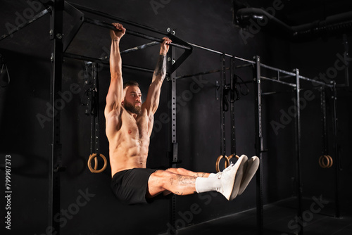 Man performing L-sit pull ups on bars, challenging bodyweight exercise. Bodyweight workout for physical and mental health.