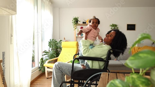 Disabled African American young mother in wheelchair takes care of her daughter at home
