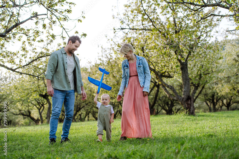 Obraz premium New parents walking with small toddler, baby, outdoors in spring nature. Older First-time parents.