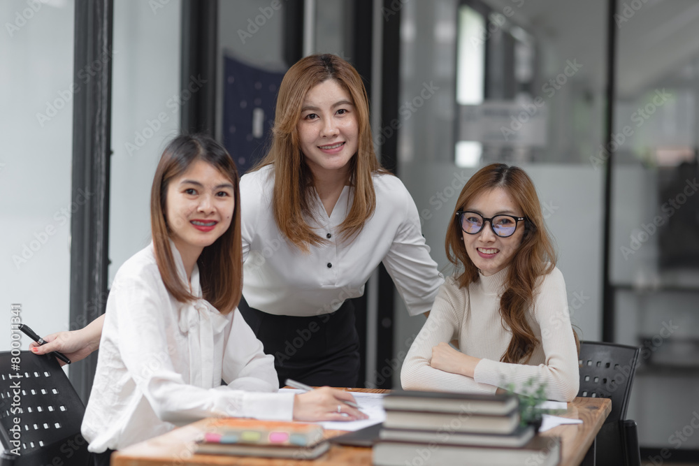 Group of young asian businesswoman working and brainstorming in workshop and analyzing marketing reports startup project infographics in the office. Group of young asian businesswoman working and brainstorming in workshop and analyzing marketing reports startup project infographics in the office.