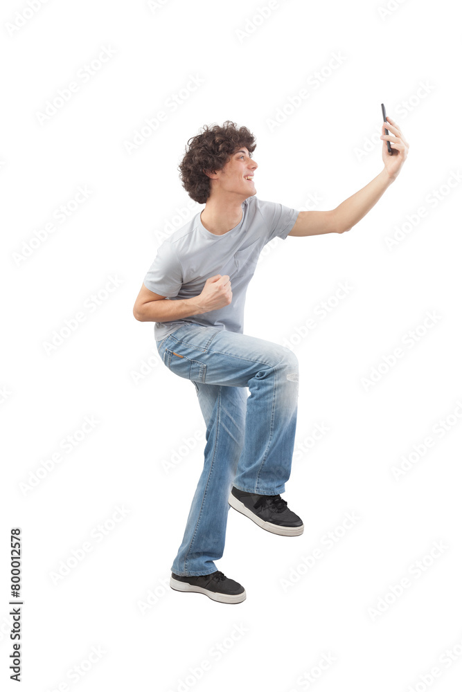 Young happy smiling handsome man elated celebrates using his smartphone in a sign of victory for the great news and goals achieved, taking a selfie isolated against a white background, full body image Young happy smiling handsome man elated celebrates using his smartphone in a sign of victory for the great news and goals achieved, taking a selfie isolated against a white background, full body image