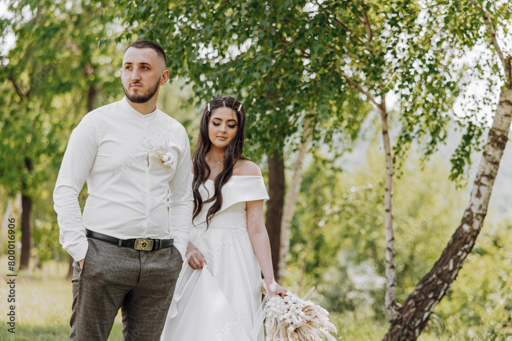 A man and woman are standing in a forest, the man is wearing a white shirt A man and woman are standing in a forest, the man is wearing a white shirt
