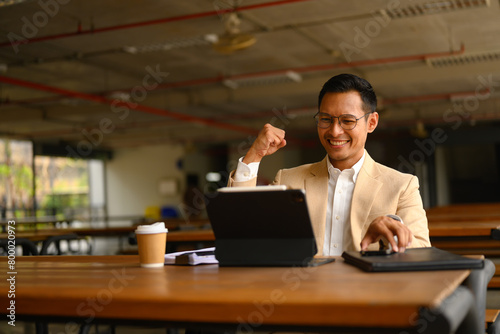 Shot of adult businessman celebrating success raising hand in yes gesture, excited by good news