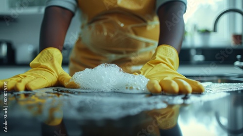 Person wearing yellow gloves and apricot washing hands in a kitchen sink with soapy water.