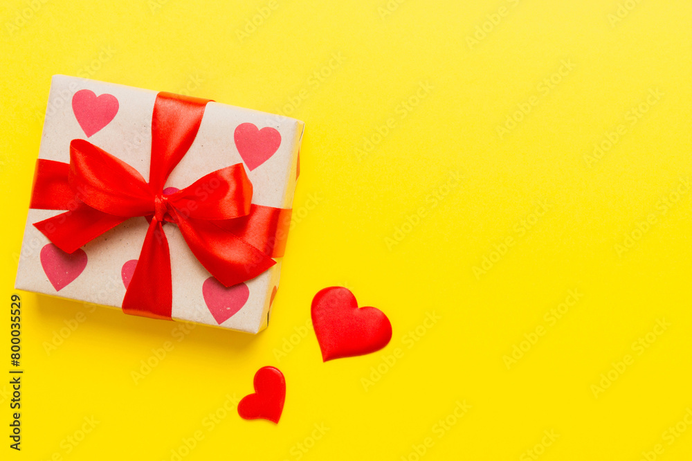 Top view photo of valentine day decorations gift box with red ribbon bow on colored background. Holiday gift boxes with top view