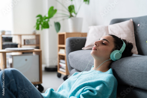 A young woman enjoys music through her headphones while lounging on the floor with vinyl records photo