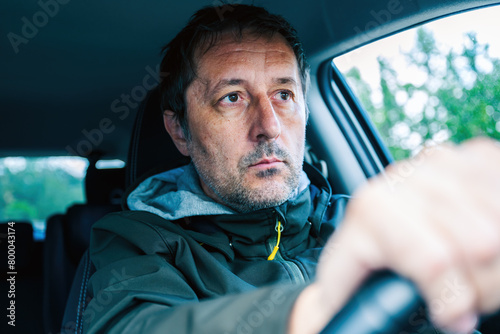 Closeup portrait of cautious male driver gripping the steering wheel and driving a car on a road trip photo