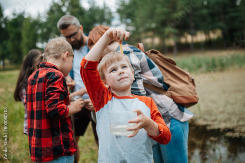 Young students analyzing water quality, ph level with indicator strips during biology field teaching class. Female teacher during outdoor active education. © Halfpoint