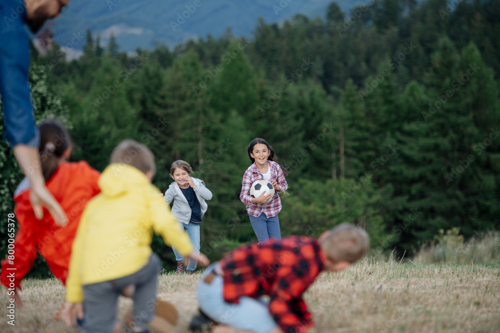 Young students playing with teacher outdoors, in nature, during field ...