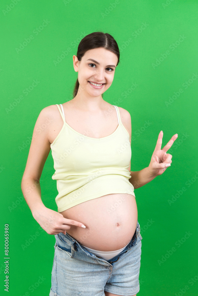 Young beautiful teenager girl pregnant expecting baby over isolated colored background smiling showing big belly Young beautiful teenager girl pregnant expecting baby over isolated colored background smiling showing big belly