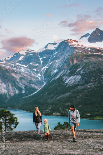 Family walking outdoor traveling together in Norway - mother, father and child on summer vacation hiking adventure active trip healthy lifestyle parents with kid enjoying fjord and mountains landscape © EVERST
