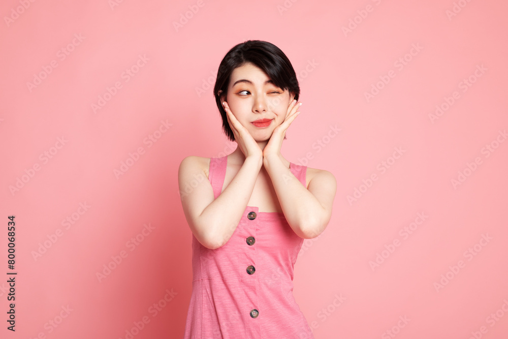 Young woman touching cheeks against pink background Young woman touching cheeks against pink background