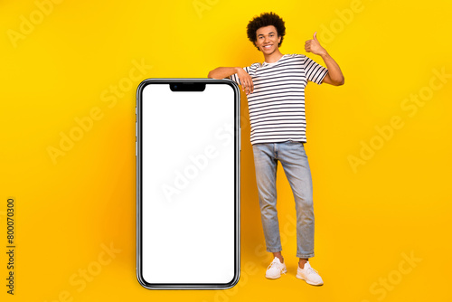 Full body length photo of youngster optimistic guy student recommend phone website menu booking service isolated on yellow color background