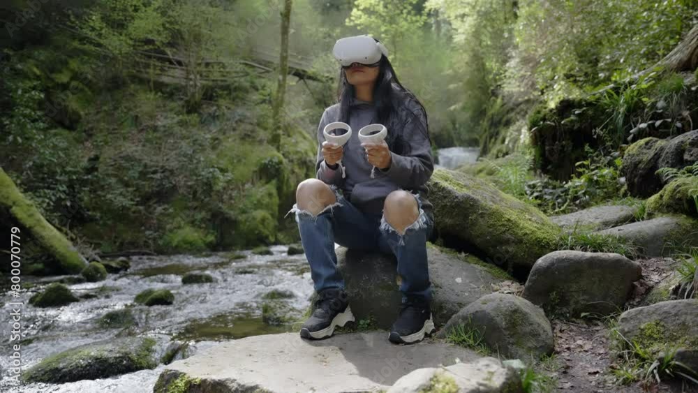 Young woman with black hair uses VR virtual reality in nature in the forest and is happy with technology Young woman with black hair uses VR virtual reality in nature in the forest and is happy with technology