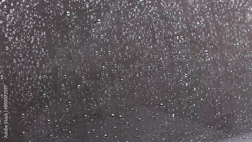 rain drops on black car window surface, closeup view from outside with slow motion photo
