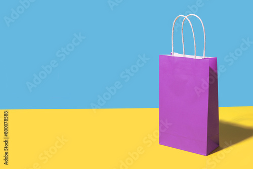 Purple shopping bag against colored background photo