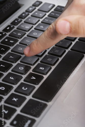 A teenager's finger above the laptop keyboard in close-up. Computer literacy